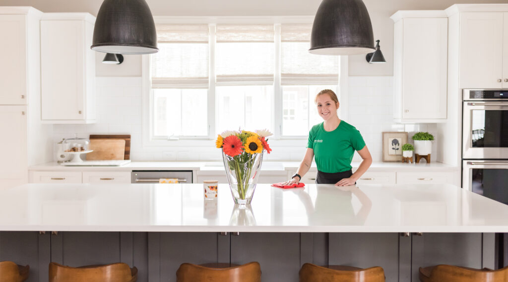 Professional home cleaner in kitchen wiping countertops